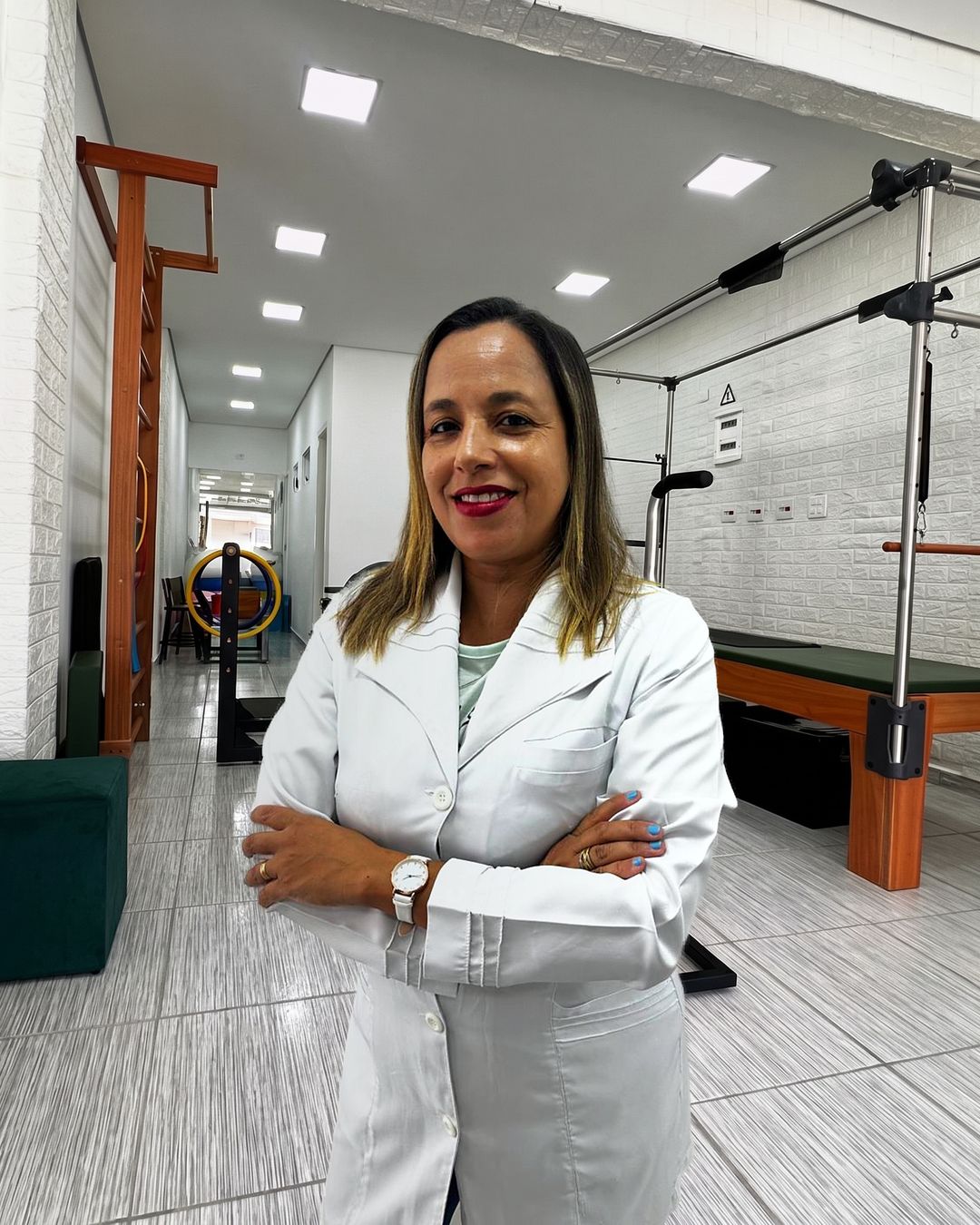 Luizangela de Jesus, de jaleco e braços cruzados, dentro do estúdio.